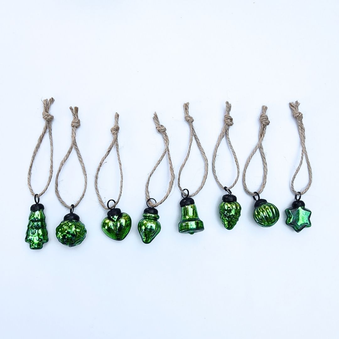Green glass Christmas baubles on string against a white background