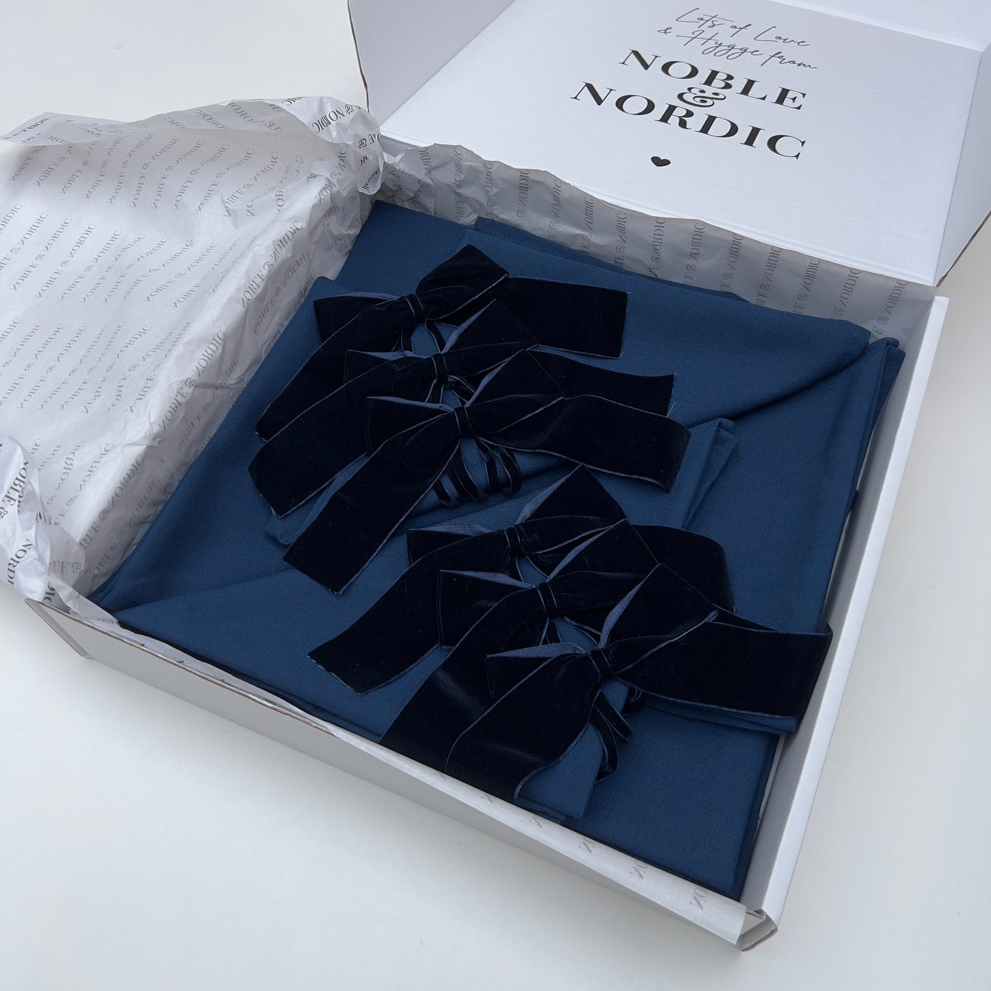 Navy velvet bow ties in a box with 'Noble & Nordic' branding on a white background