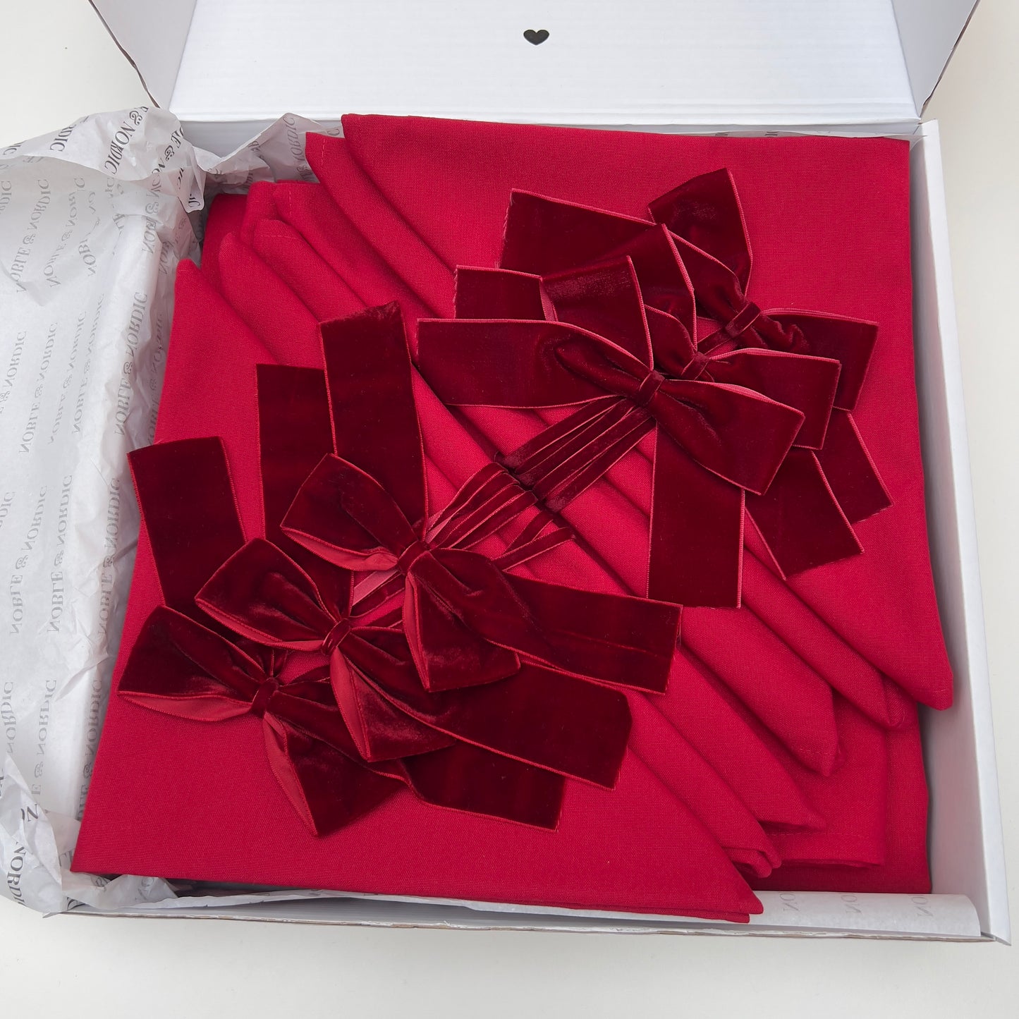Burgundy velvet bows arranged in a decorative pattern inside an open box.