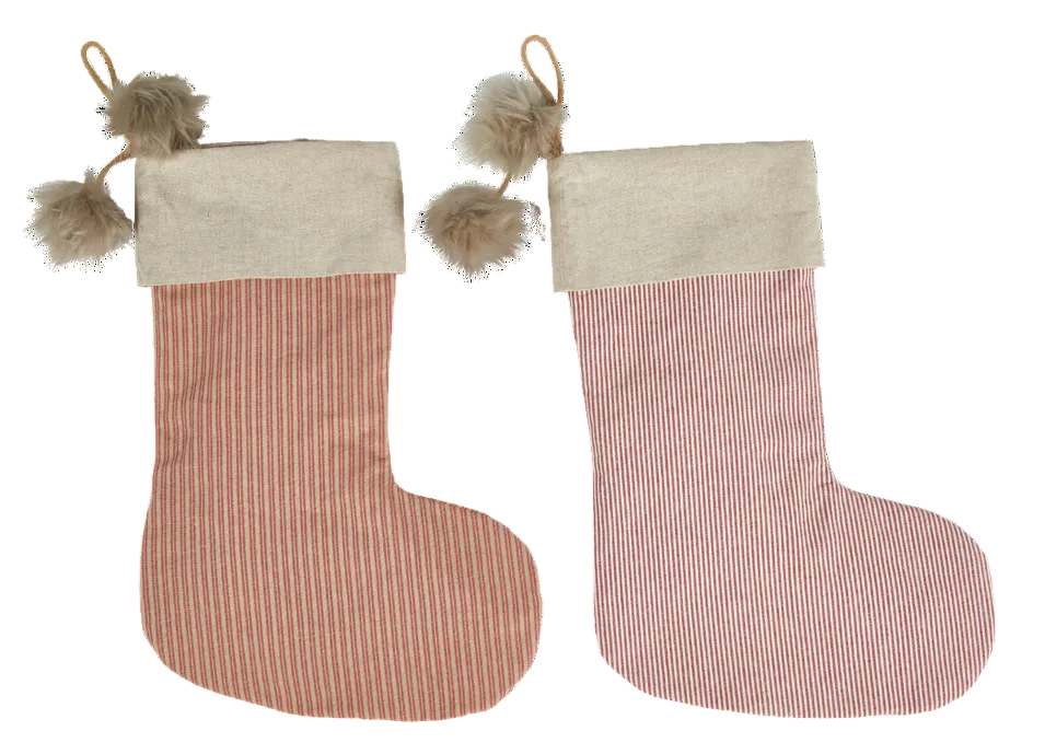 Two Christmas stockings side by side on a white background. The left stocking is dusty rose pink with thin white vertical stripes and a light beige fabric cuff with two beige faux-fur pom-poms.