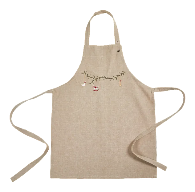 A beige linen apron with a delicate embroidered design of a green vine branch, small birds, and a tiny red-and-white birdhouse across the chest, displayed on a clean white background.