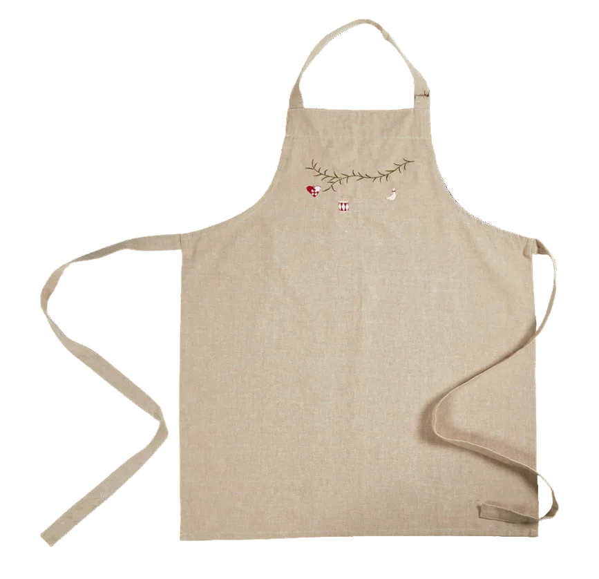 A light beige linen apron with a small embroidered holiday garland design near the neck strap, featuring a tiny red bird, a red-and-white checkered flag, and a small white bird, shown on a plain white background.