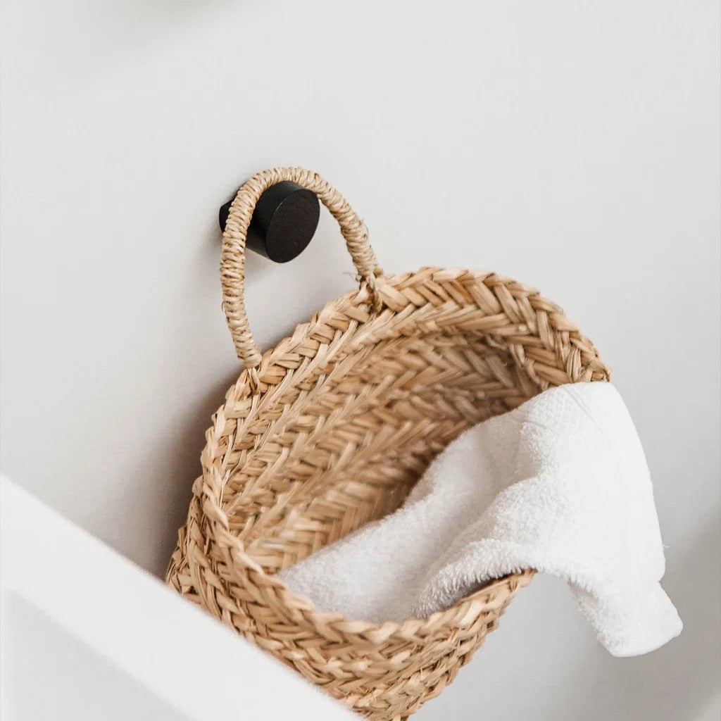 Woven basket with a white towel on a light gray wall