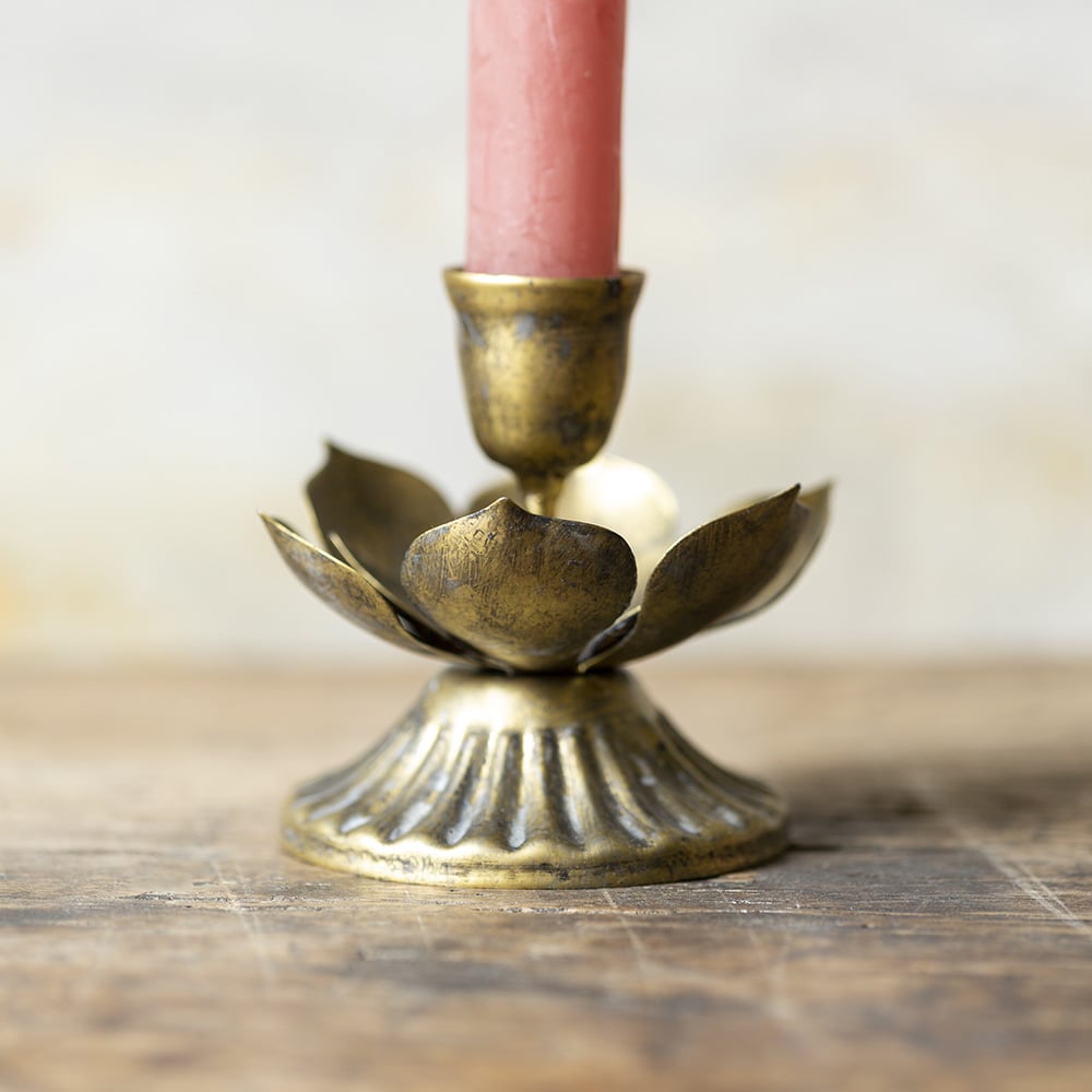 Antique brass lotus candle holder with layered metal petals reflecting soft candlelight.