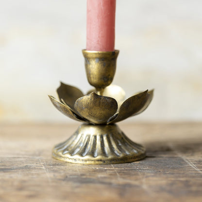 Antique brass lotus candle holder with layered metal petals reflecting soft candlelight.