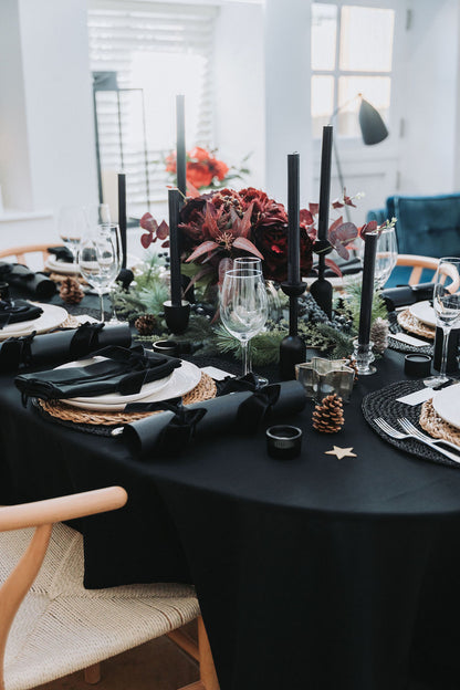 Elegant dining table setting with black tablecloth, black candles, and decorative elements by Noble & Nordic.