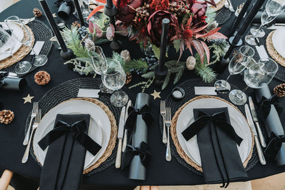 Elegant table setting with black napkins, silverware, and decorative elements on a black tablecloth by Noble & Nordic.