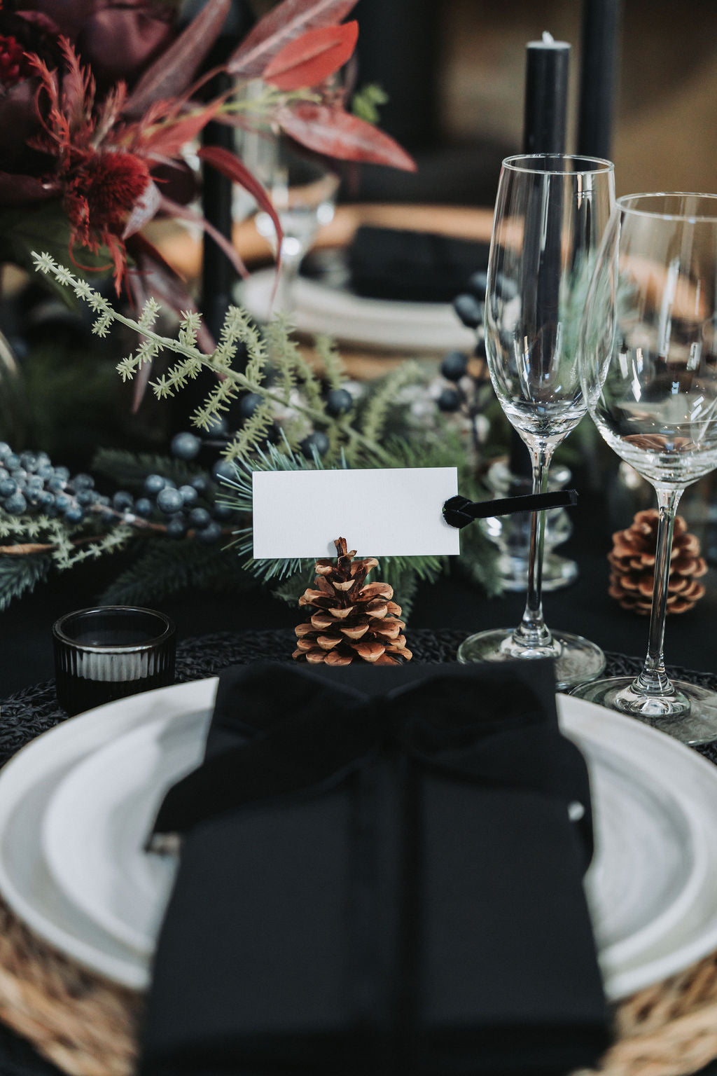 Dining table setting with black napkin, white plate, and decorative elements by Noble & Nordic.