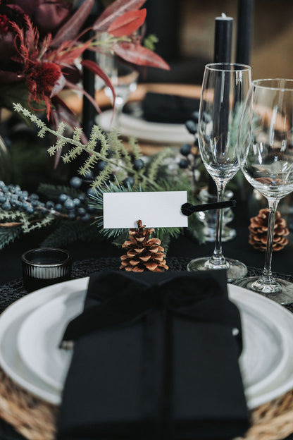 Dining table setting with black napkin, white plate, and decorative elements by Noble & Nordic.