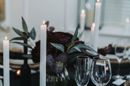 Decorative table setting with white taper candles, flowers, and wine glasses by Noble & Nordic.