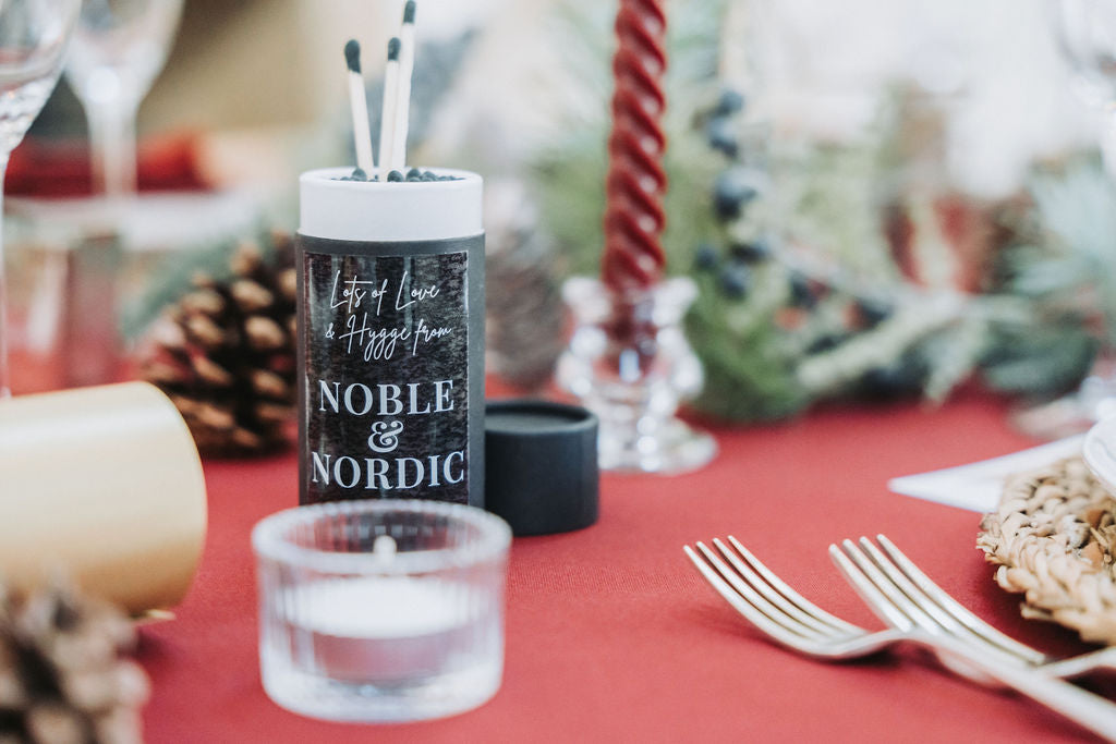 Noble & Nordic matchsticks on a festive Christmas table setting with dark red candles and decorations, designed by Noble & Nordic.