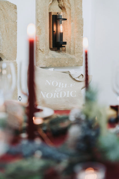 Decorative setting with red candles and a 'Nordic' sign in a cozy interior, by Noble & Nordic.