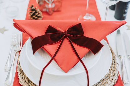 Scandinavian-inspired red Christmas table setting with velvet bows and candlelight by Noble & Nordic.