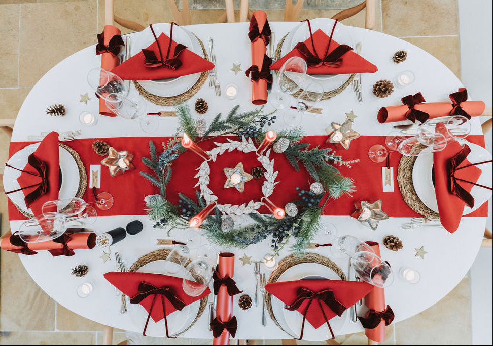 Nordic red Advent table styled with red candles, burgundy velvet ribbons, and festive fir pine cone Christmas garland  by Noble & Nordic.