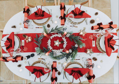 Nordic red Advent table styled with red candles, burgundy velvet ribbons, and festive fir pine cone Christmas garland  by Noble & Nordic.