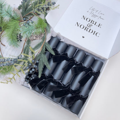 Box of black Christmas crackers with black velvet bows with 'Noble & Nordic' branding on a decorative gift box by Noble & Nordic.