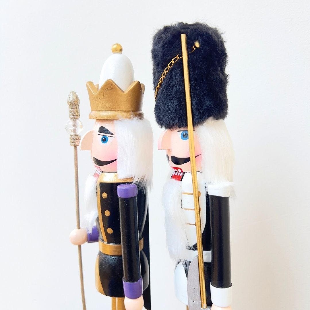 Two decorative nutcrackers with royal and guard hats on a white background