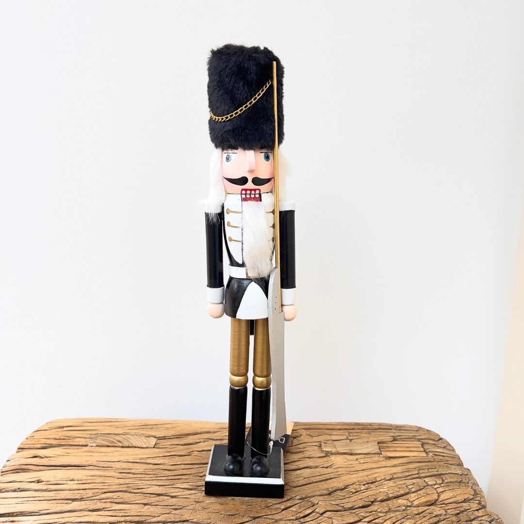 Wooden nutcracker figurine on a wooden surface with a white background