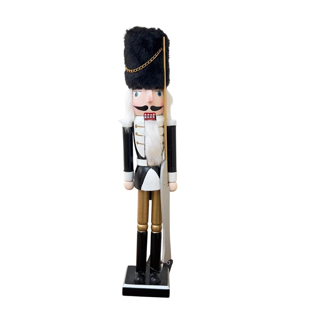 Nutcracker figurine in traditional uniform with black hat and white outfit on a white background