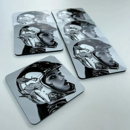 Set of four metallic coasters with black and white illustrations on a light gray background