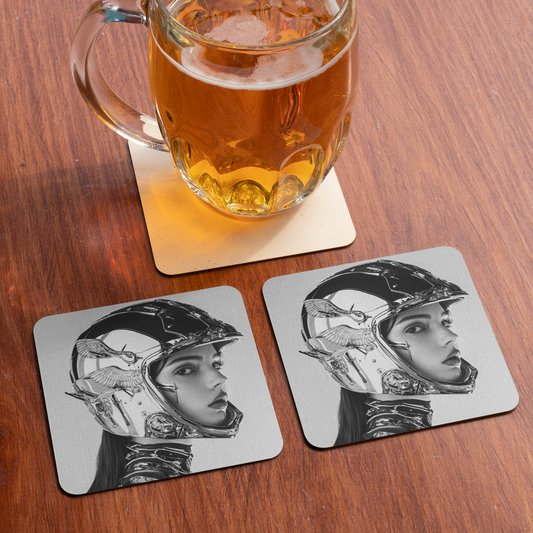 Glass of beer on a coaster with cool biker chick design, placed on a wooden surface.