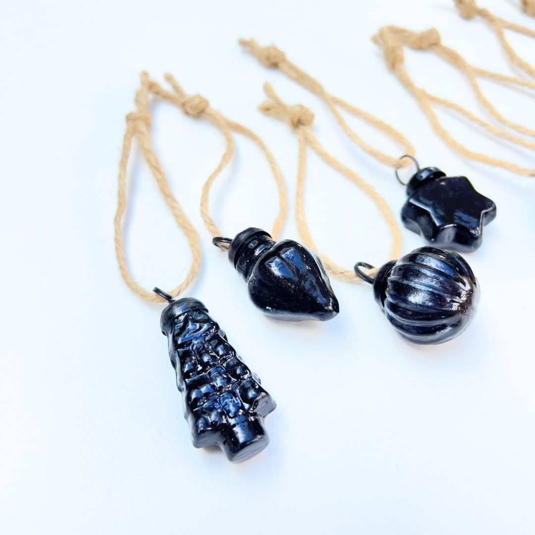 Black decorative Christmas baubles on beige jute strings against a white background