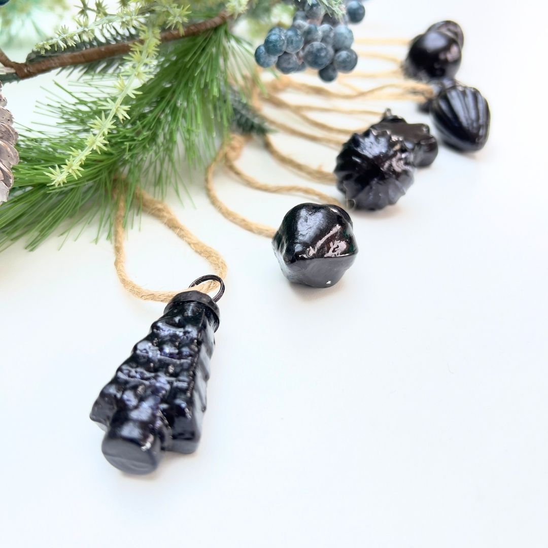 Black decorative Christmas mini baubles on a jute string with Christmas garland greenery and berries on a white background