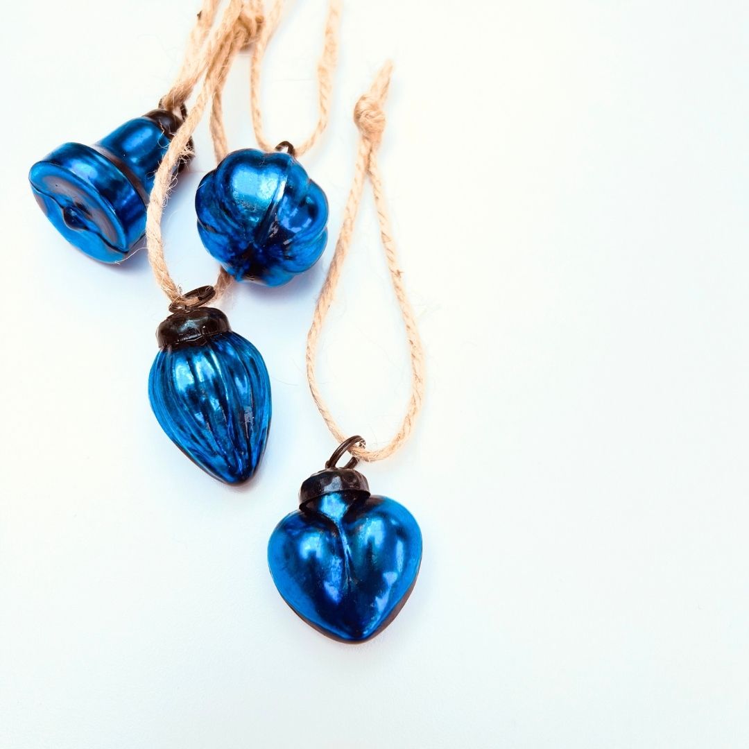 Blue heart-shaped glass Christmas mini baubles and mixed shaped baubles on a white background