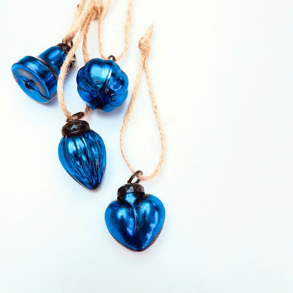Blue heart-shaped glass Christmas mini baubles and mixed shaped baubles on a white background