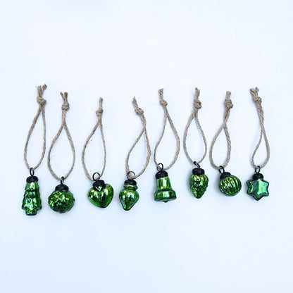 Green glass Christmas baubles on string against a white background
