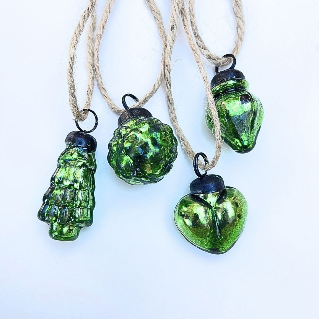 Green glass Christmas baubles on strings against a white background