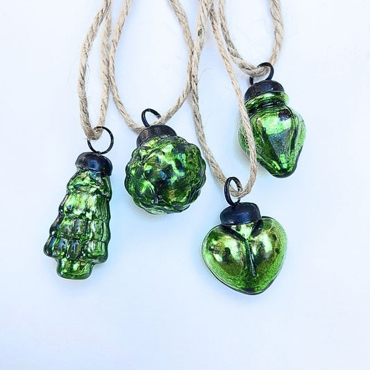 Green glass Christmas baubles on strings against a white background