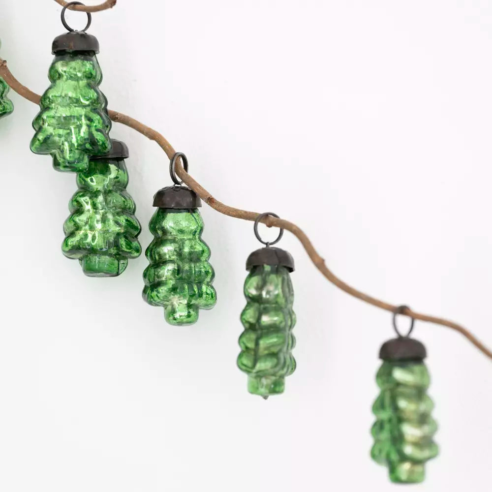 Close-up of green glass Christmas tree baubles hanging from a natural branch — timeless Nordic-inspired festive decorations by Noble & Nordic.