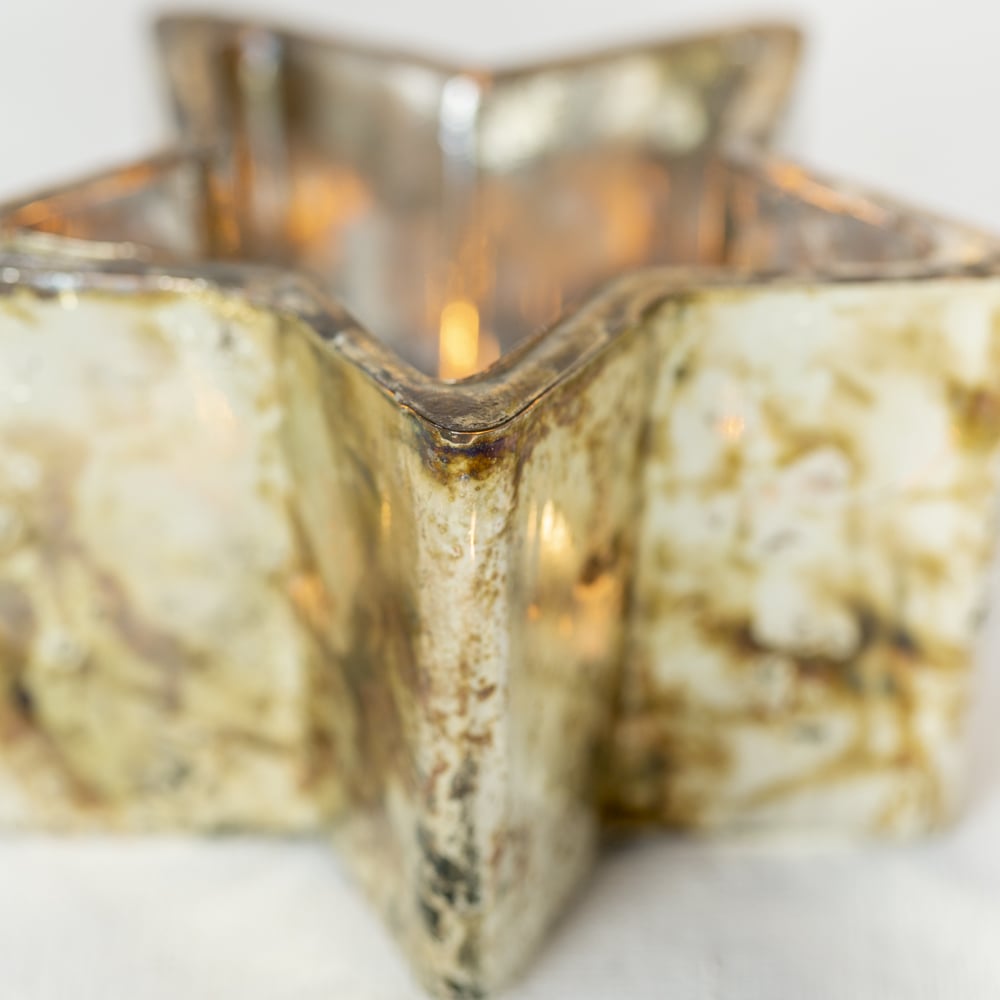 Glass starry night tealight holder in copper with silver interior casting soft candlelight.