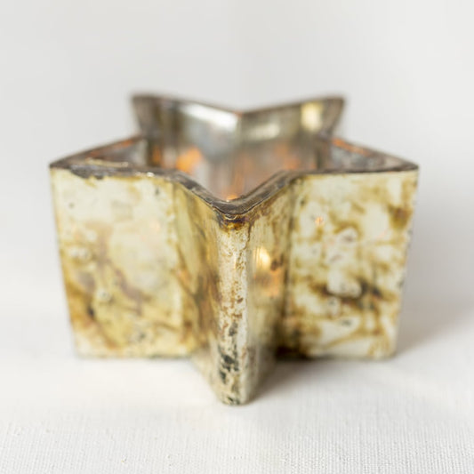 Close-up of copper tealight holder with perforated star design glowing warmly.